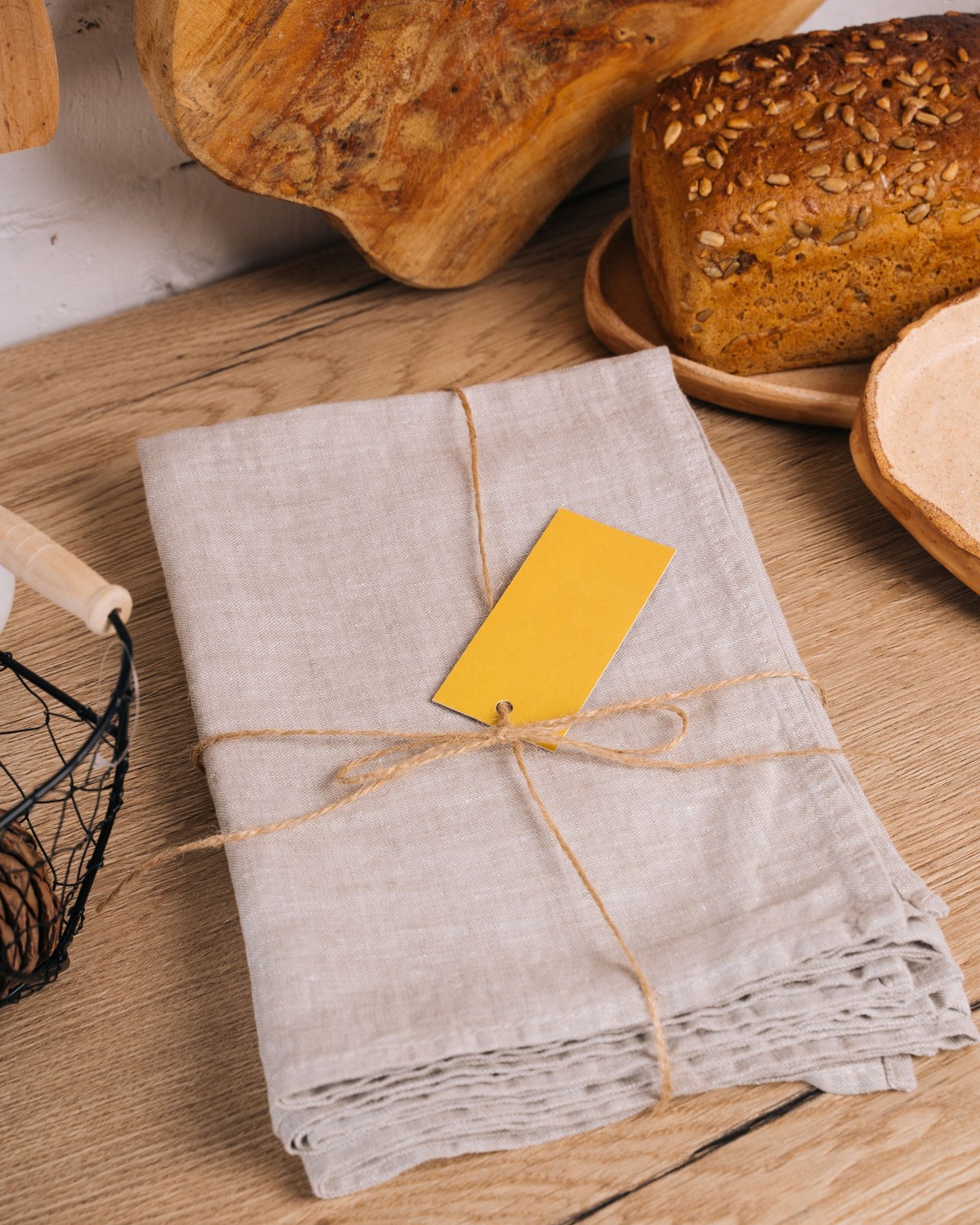 Folded natural linen napkins beside a freshly baked loaf on a wooden counter